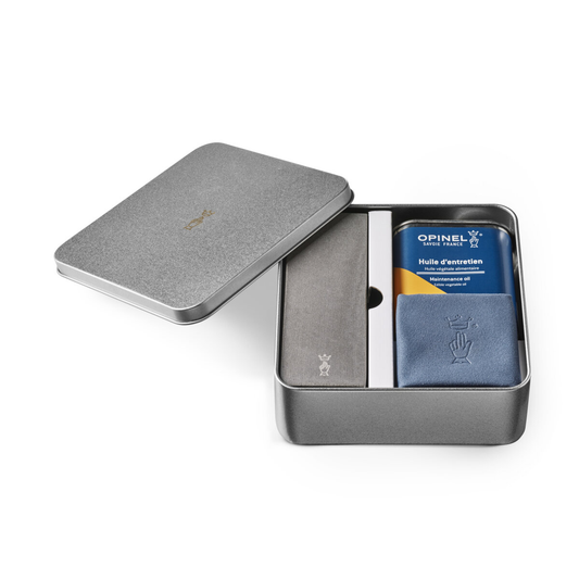 Open gray metal tin containing a blue card and a silver knife, branded 'Opinel'.