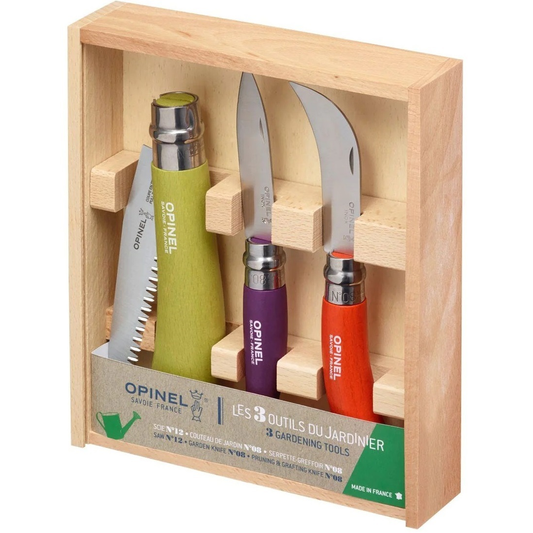 Opinel 3-piece gardening tool set in a light wood presentation box. The set includes a green-handled weeding tool, a purple-handled pruning tool, and an orange-handled shears tool, all with silver stainless steel blades and secured in wooden slots.