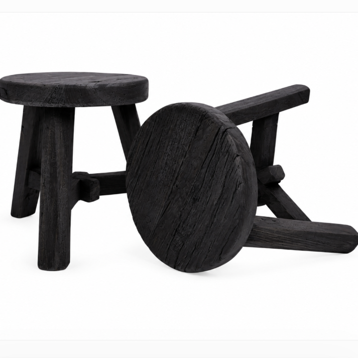 A pair of rustic black wooden stools, one standing upright and the other lying on its side to show the backrest, on a plain white background.