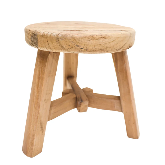 A small round wooden stool with a natural light brown finish, featuring a thick circular seat and three angled legs connected by a central crossbar, 