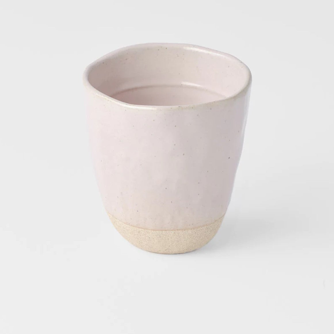 A Sakura Pink lopsided ceramic mug with a two-tone design, featuring a solid pink color on the upper part and a natural clay color on the lower part.