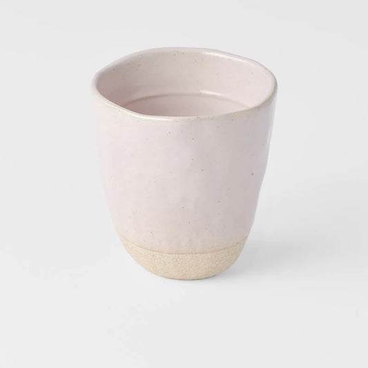 A Sakura Pink lopsided ceramic mug with a two-tone design, featuring a solid pink color on the upper part and a natural clay color on the lower part.