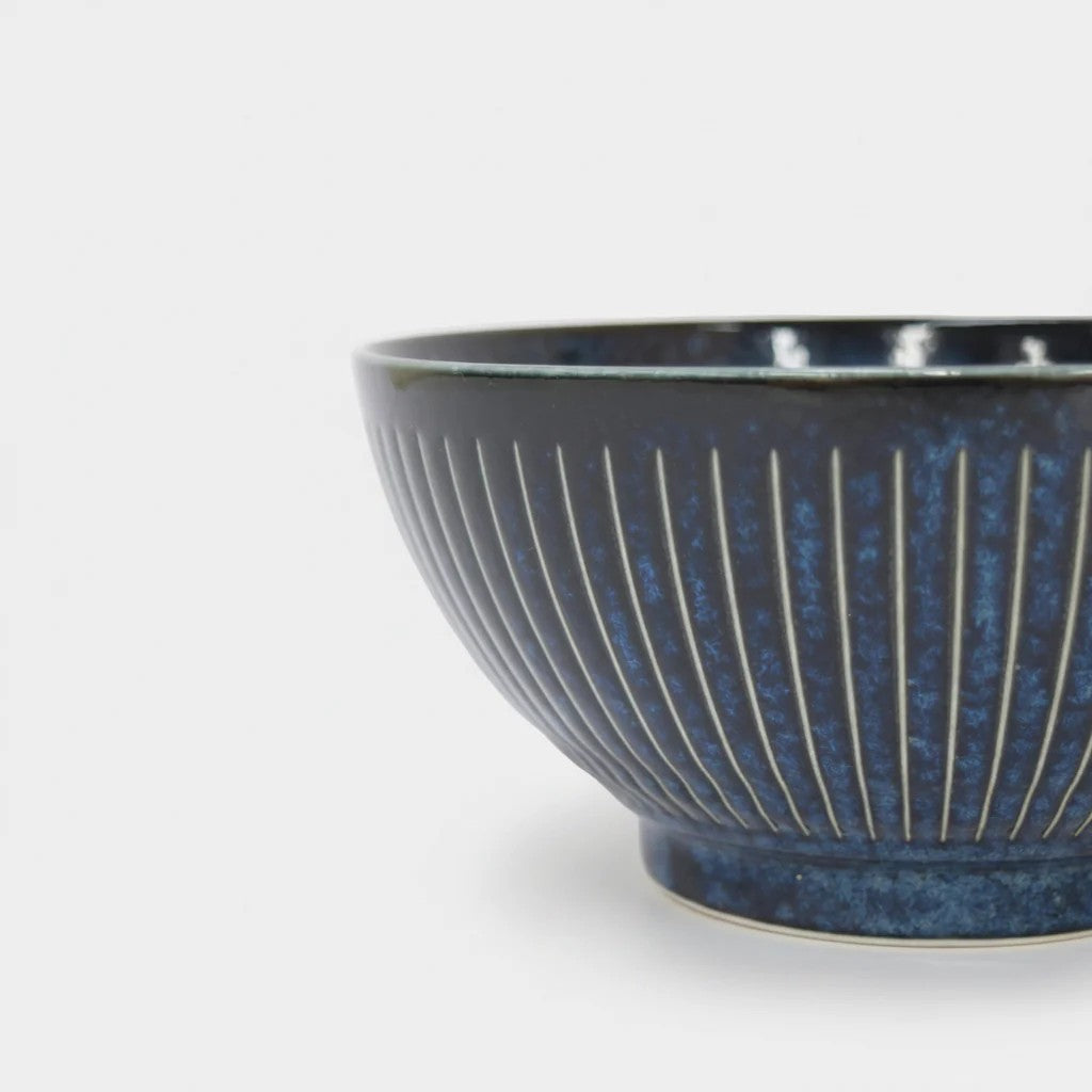 Blue ceramic bowl with ribbed texture on a light gray background