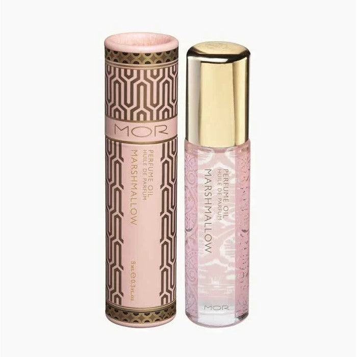 MOR Marshmallow Perfume Oil in a small, clear glass bottle with a gold-colored cap, displayed next to its packaging tube which has a pink and gold color scheme.