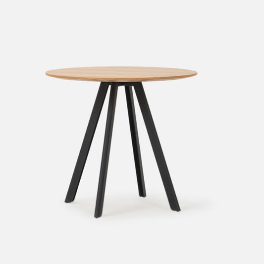 A round dining table with a oak wood tabletop and black steel legs with a visible base plate.