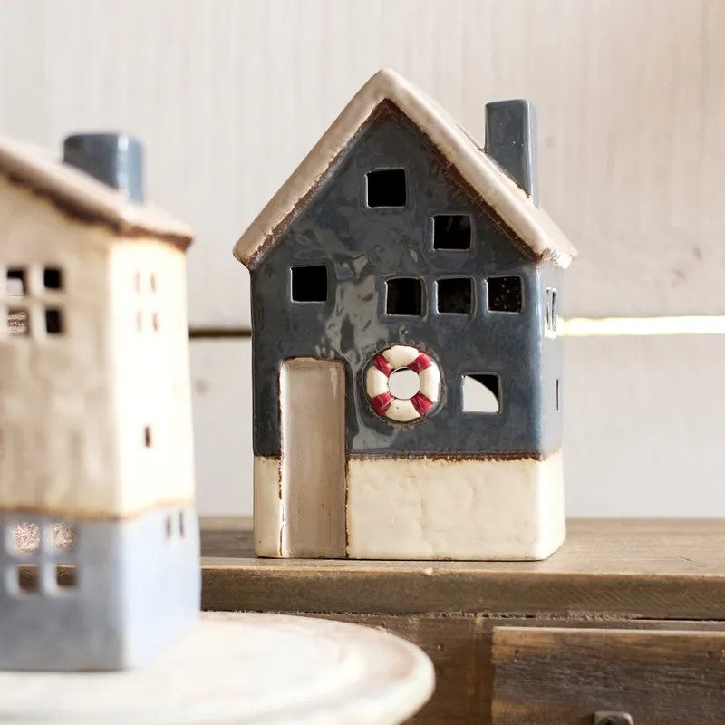Ceramic house-shaped lantern with a life buoy design on a wooden surface.