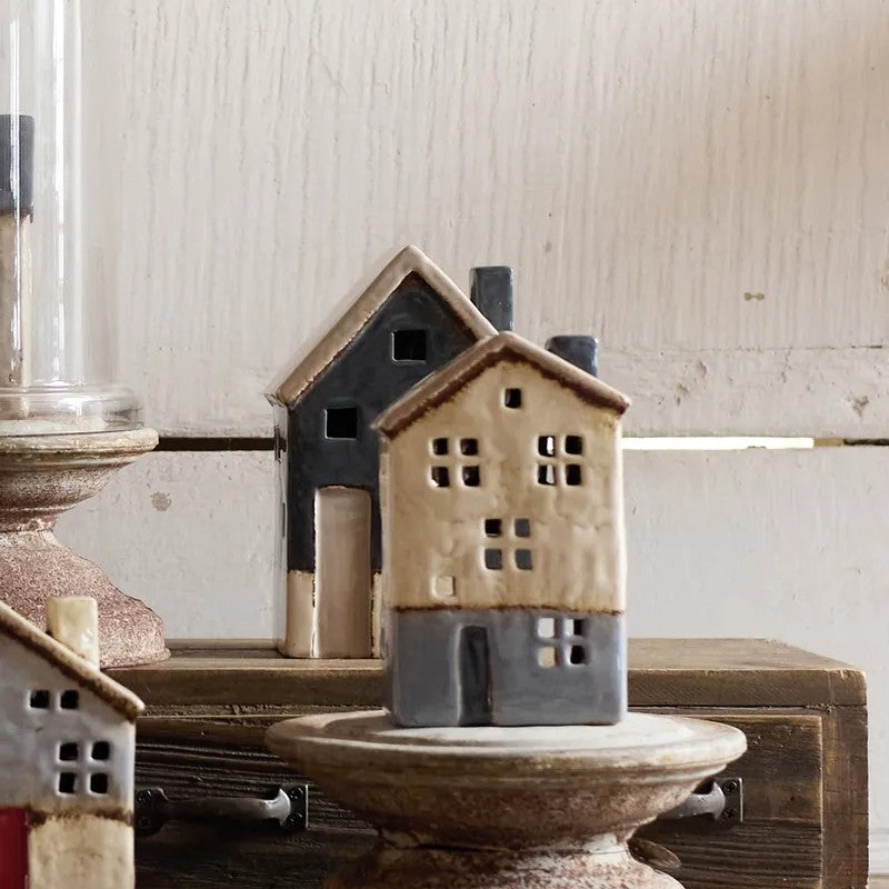 Small ceramic house on a wooden surface with a neutral background