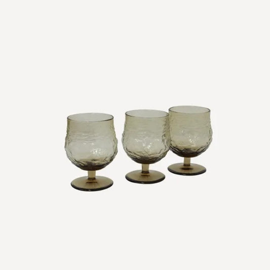A set of four brown glass wine goblets with an irregular shape,