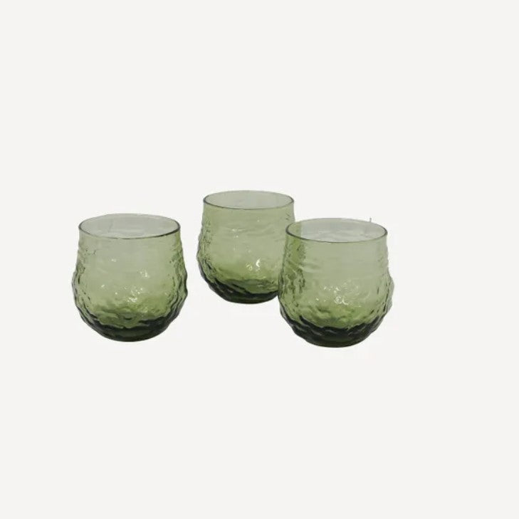 A set of four green glass tumblers with an irregular shape,