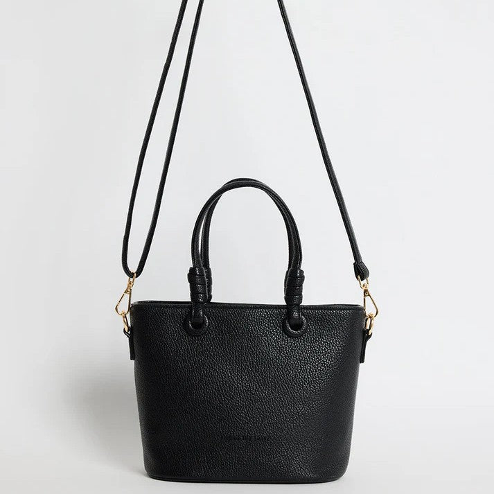 Black handbag with a strap on a light gray background