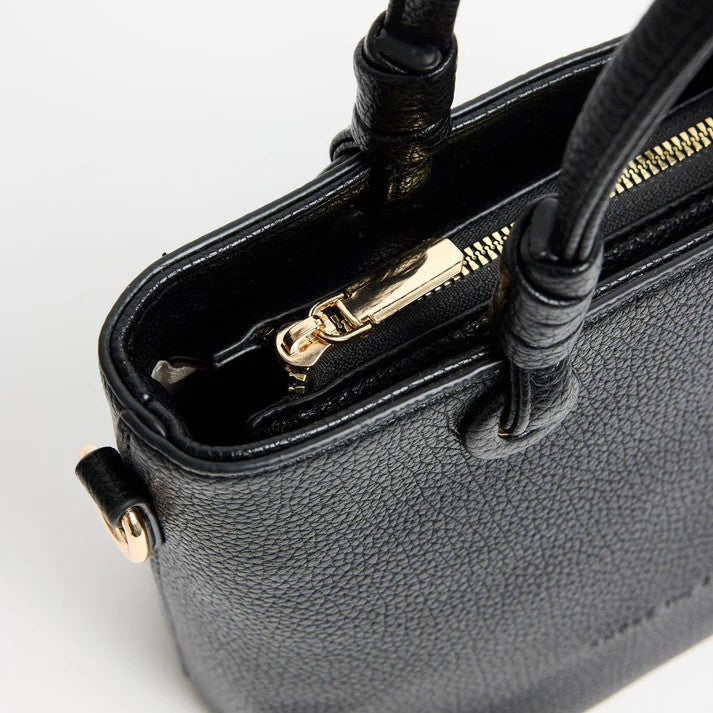 Black handbag with gold zipper on a light gray background