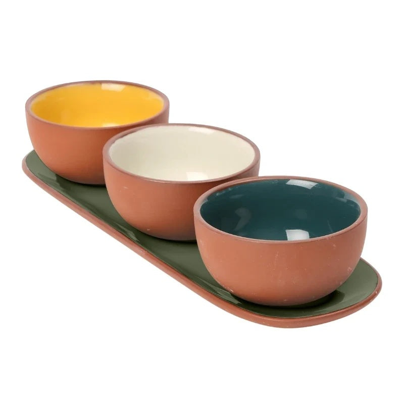 Three ceramic bowls in terracotta with contrasting interiors in yellow, off-white, and teal, arranged on a matching green rectangular tray 