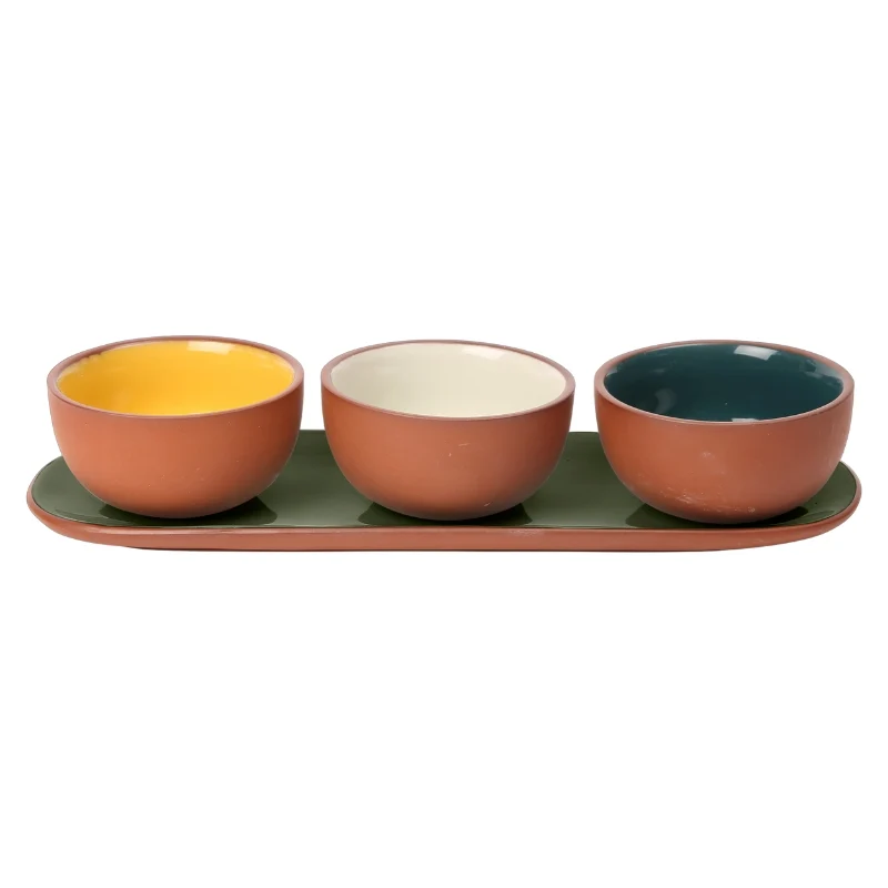 Three ceramic bowls in terracotta, mustard yellow, cream, and teal, arranged on a matching terracotta serving tray.