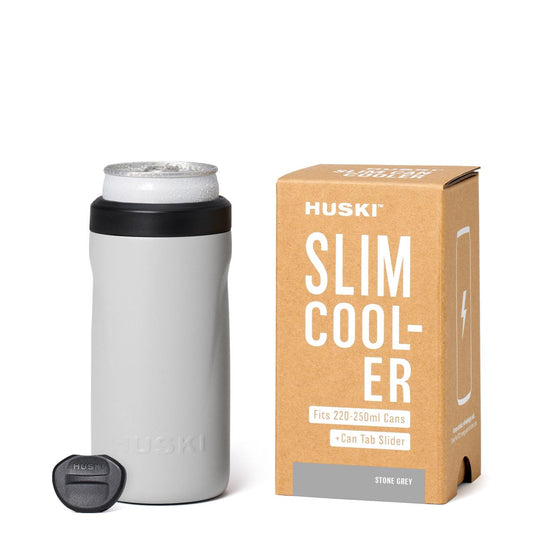 Grey slim cooler with black lid and Huski branding next to its packaging on a white background