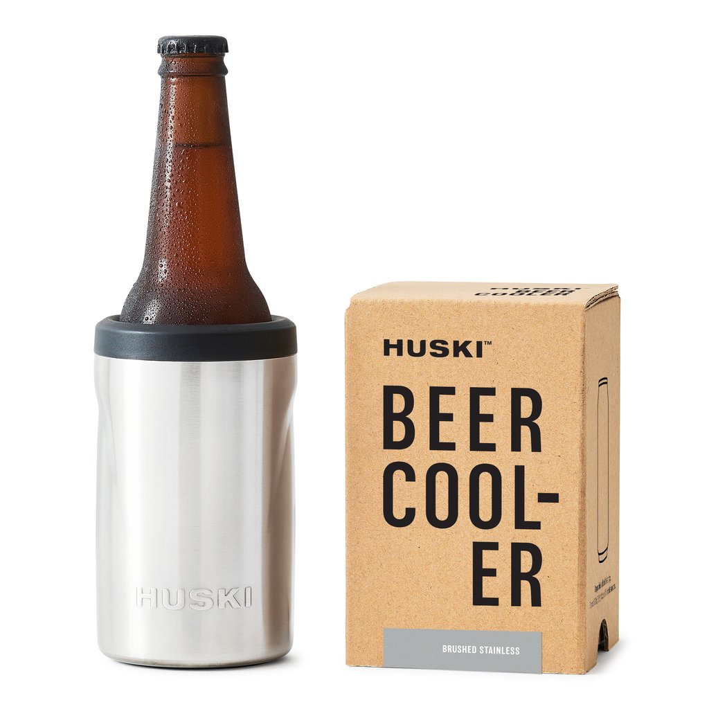 A brushed stainless steel Huski Beer Cooler with a bottle inserted, next to its packaging box.