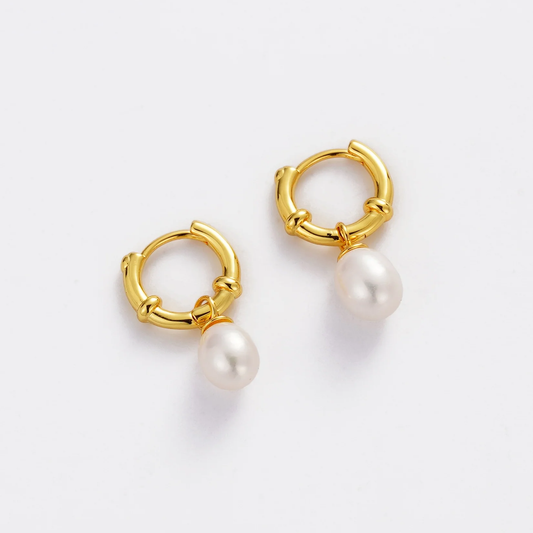 Gold hoop earrings with pearl drops on a light gray background