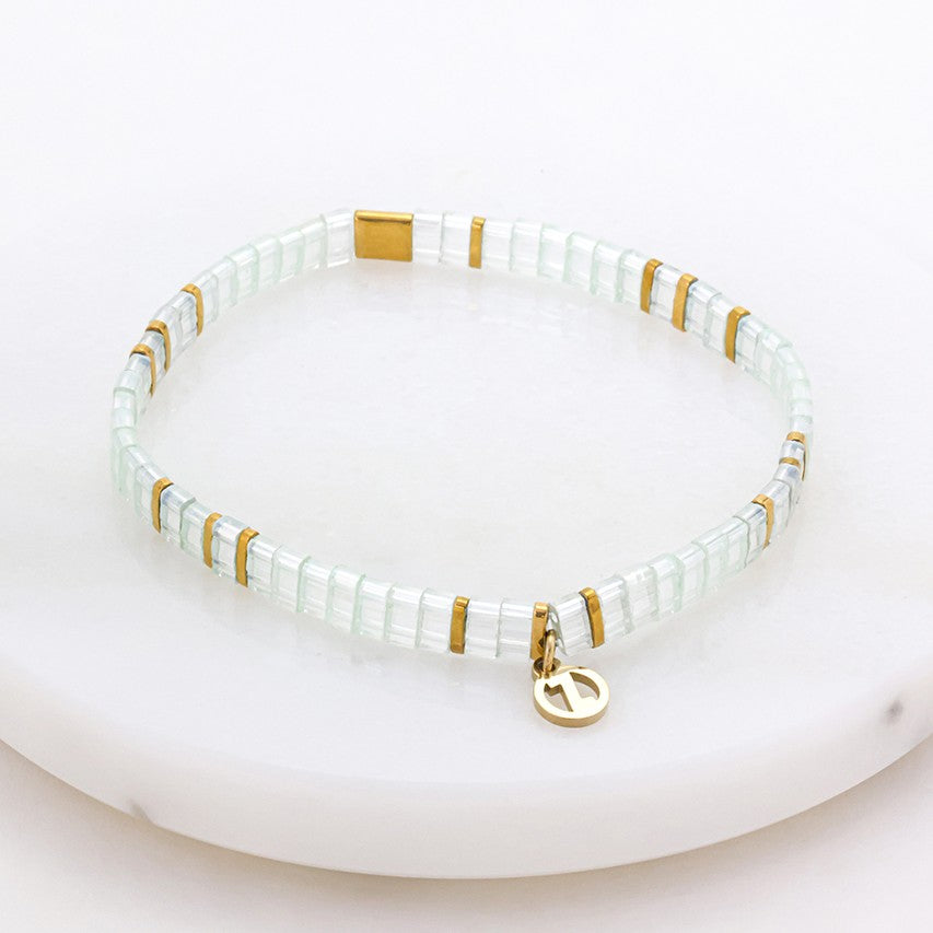 Bracelet with white beads and gold accents on a white background 