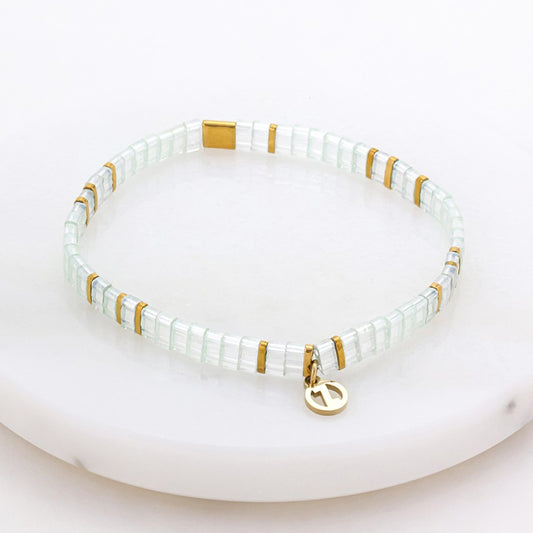 Bracelet with white beads and gold accents on a white background 