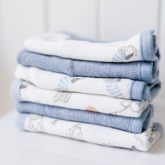 Stack of folded baby face cloths with animal patterns on a light background