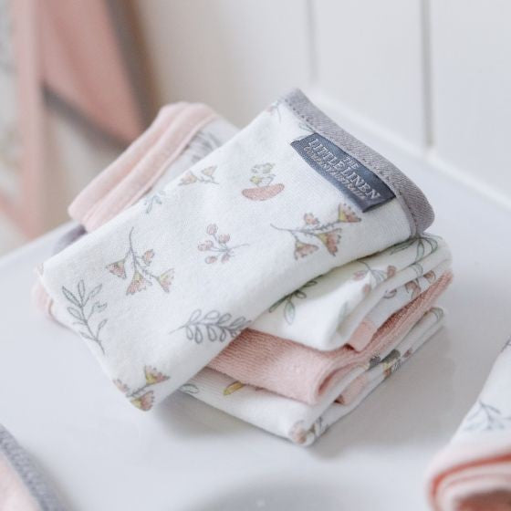 Stack of folded baby wash cloths with floral patterns on a white surface