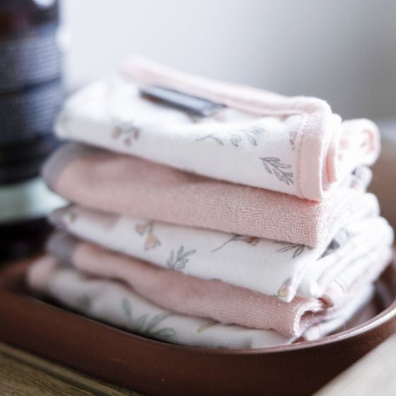 Stack of folded baby wash cloths with floral patterns on a wooden surface