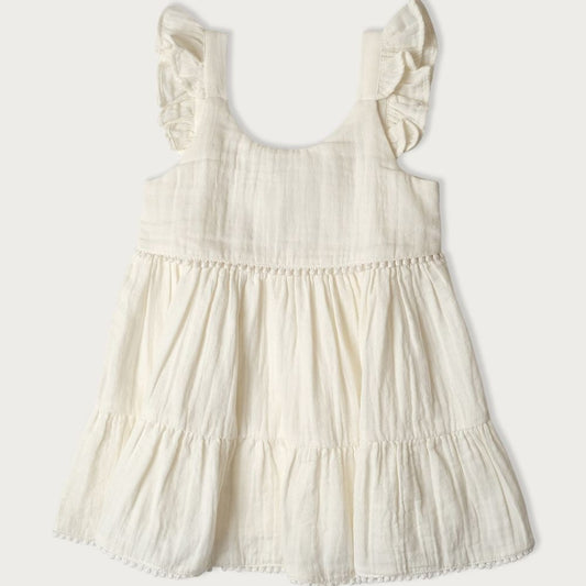 A white, short-sleeved baby dress with embroidered pompoms and ruffles on the shoulders
