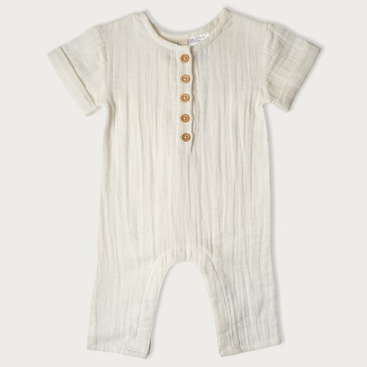 A beige-colored baby romper with short sleeves, wooden buttons down the center, and snap domes at the legs.