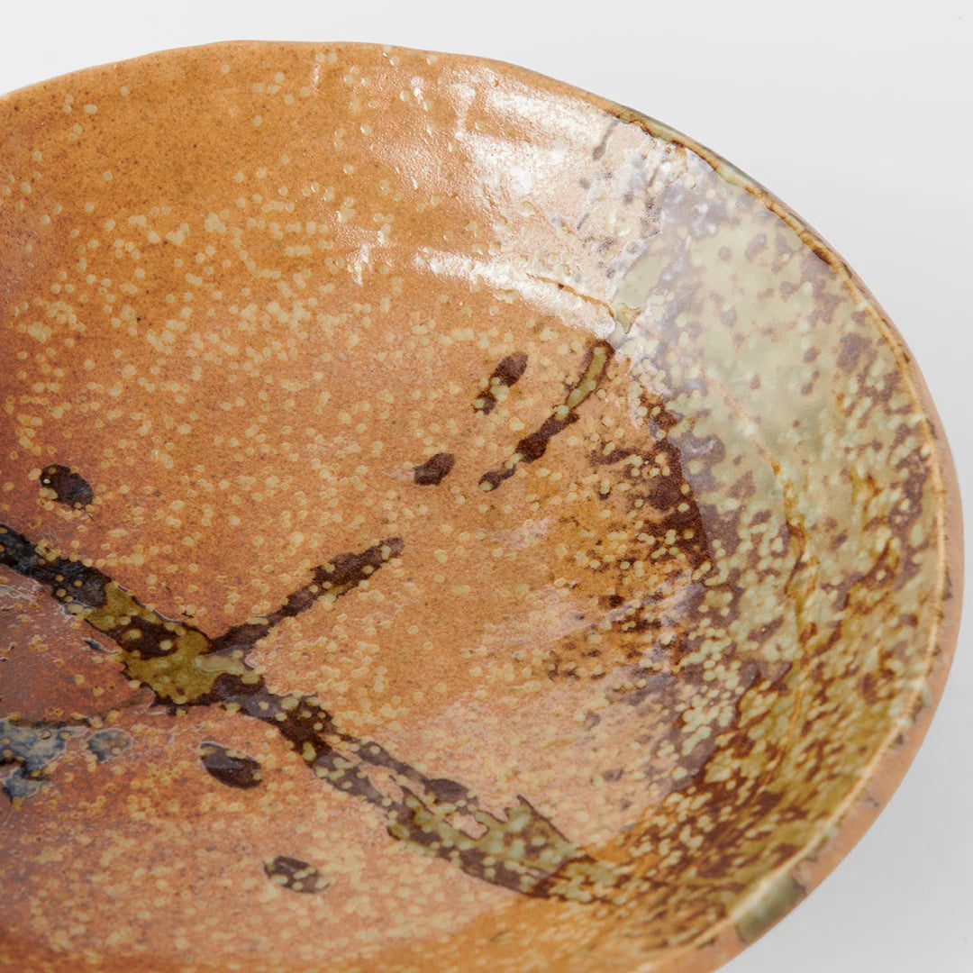 Brown ceramic plate with speckled glaze on a white background