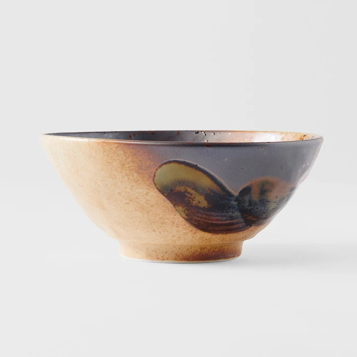 A handmade ceramic bowl with a speckled beige exterior and a glossy dark brown glazed interior, featuring a large organic, shell-like brown and olive-green glaze pattern on the side, 
