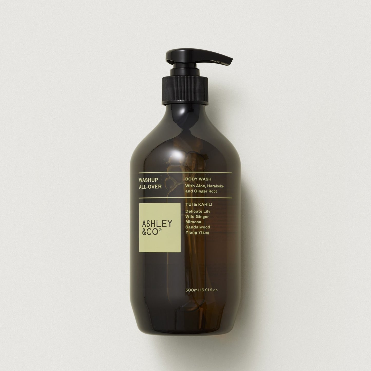 Ashley & Co Mashup All-Over body wash in a dark amber glass bottle with a black pump dispenser and a cream label, set against a light gray background.