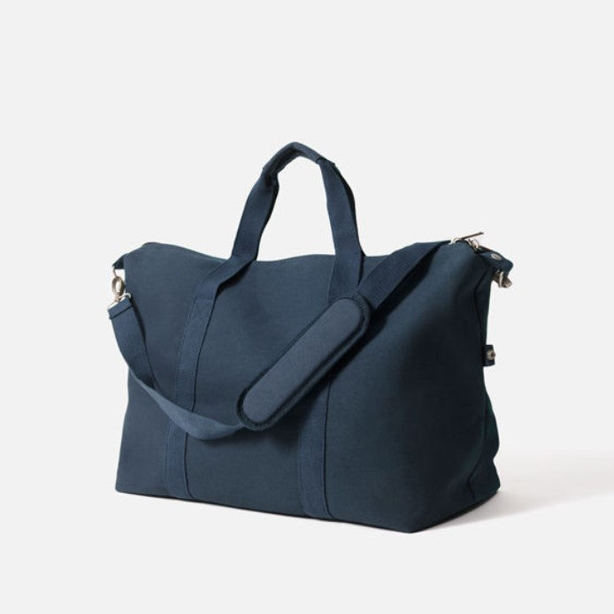 A navy-colored Citta canvas weekender bag with a zippered top, two handles, and an adjustable shoulder strap.