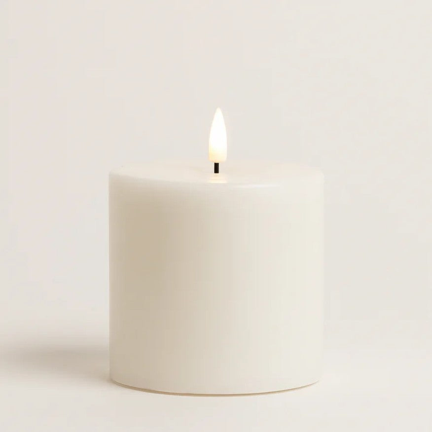 White battery operated candle with a lit wick 
