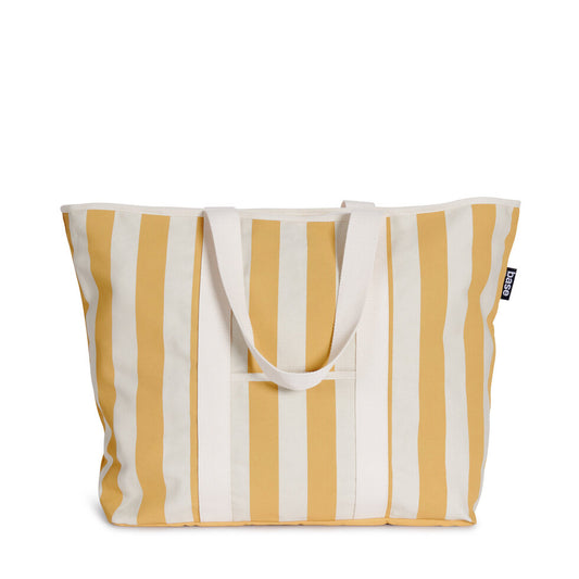 A canvas shopper bag with mustard yellow stripes and a tan background, featuring a front storage pocket and a zip top closure.
