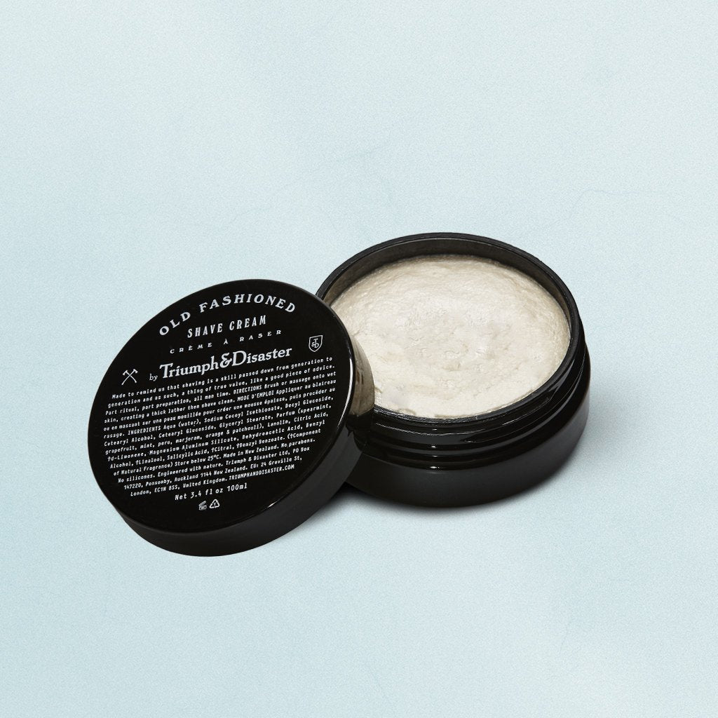 A jar of Triumph & Disaster Old Fashion Shave Cream with the lid off, showing the white cream inside.