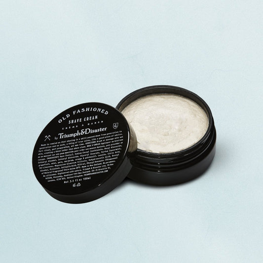 A jar of Triumph & Disaster Old Fashion Shave Cream with the lid off, showing the white cream inside.